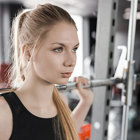 A girl with a barbell on her shoulders.
